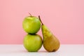 The composition of two fresh green apples and one long pear on pink background Royalty Free Stock Photo