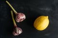 Composition of two onions of garlic and lemon on a black background. Royalty Free Stock Photo