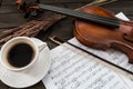 Composition with violin, cup of coffee, music sheets on wooden table Royalty Free Stock Photo