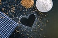 Composition with wheat grains, flour with heart shape on black background Royalty Free Stock Photo