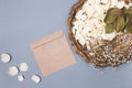 Composition with white dry petals of a pink flower on an old brass tray and an envelope from kraft paper on a gray background in