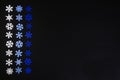 A composition of white, light blue, and blue snowflakes arranged vertically on a black background. Royalty Free Stock Photo