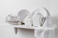 Composition of white wood hanging shelf on wall with country home tableware set on display. Royalty Free Stock Photo