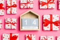 Composition of wooden calendar and holiday white gift boxes with red hearts on colorful background. The fourteenth of february. Royalty Free Stock Photo