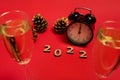 Composition with wooden numerals, 2022 year, black alarm clock with midnight on the clock face, golden pine cones and champagne