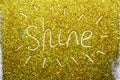 A composition with written a word shine on beautiful gold glitter. Background and texture of gold glitter. Luxury gold glitter