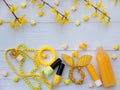 Composition of yellow accessories for young girl or teenager. Nail polishes, lipstick, hair clips, bands, beads, bracelet, perfum