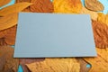 Composition with yellow and brown autumn leaves and blue paper mockup on blue pastel background. side view, copy space Royalty Free Stock Photo