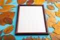 Composition with yellow and brown autumn leaves and wooden frame mockup on blue pastel background. side view, copy space Royalty Free Stock Photo