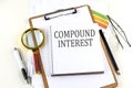 COMPOUND INTEREST text on notebook with clipboard on white background Royalty Free Stock Photo