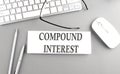 COMPOUND INTEREST text on paper with keyboard on grey background Royalty Free Stock Photo