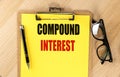 COMPOUND INTEREST text on yellow paper on clipboard with pen and glasses Royalty Free Stock Photo