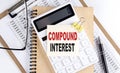COMPOUND INTEREST word on sticky with clipboard and notebook, business concept Royalty Free Stock Photo