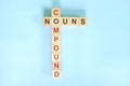 Compound nouns concept in English grammar noun education. Wooden block crossword puzzle flat lay in blue background.