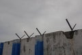 Compound wall and barbwire holders, dark clouds background Royalty Free Stock Photo