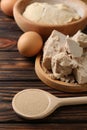 Compressed and dry granulated yeast, eggs and dough on wooden table