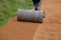 Compressing the gravel of the new park threshing path. lawn seed is repaired by rolling a metal hand roller, which is filled with