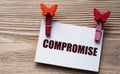 COMPROMISE - word on a white sheet with beautiful clothespins on a wooden background