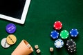 Compulsive gambling. Poker chips and the dice nearby tablet on green table top view copyspace