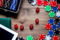 Compulsive gambling. Poker chips and the dice nearby tablet on wooden table top view copyspace