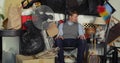 Compulsive hoarding disorder concept - man hoarder sitting in the chair and looking on his stuff piles