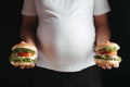 Overweight man with two tasty hamburgers