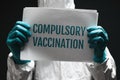 Compulsory vaccination note on poster, medical worker holding paper with text