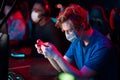 At the computer club, a cute guy in a medical mask plays a game through an app on his smartphone Royalty Free Stock Photo