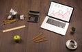 Computer desk with laptop and red arrow chart in screen Royalty Free Stock Photo