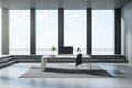 Computer on a desk standing in the middle of an empty bright room with black columns, stairs and big windows, concrete floor, Royalty Free Stock Photo