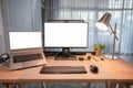 Computer device with blank monitor, laptop, table lamp, keyboard, mouse on wooden desk in home office Royalty Free Stock Photo