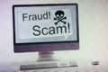 Computer displaying internet fraud and scam warning on screen