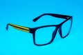 Computer eye protection glasses with a yellow shackle close up on a blue background, isolation