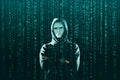 Computer hacker in mask and hoodie over abstract binary background. Obscured dark face. Data thief, internet fraud Royalty Free Stock Photo