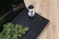 Laptop computer, Christmas tree branch and a snowman on a wooden