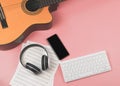 Computer keyboard, headphones, mobile phone, music sheets and acoustic guitar on pink background with copy space. Musician, Royalty Free Stock Photo
