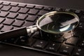 Computer keyboard and magnifying glass, close-up. Computer security concept Royalty Free Stock Photo