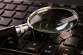 Computer keyboard and magnifying glass, close-up. Computer security concept