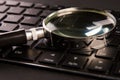 Computer keyboard and magnifying glass, close-up. Computer security concept Royalty Free Stock Photo