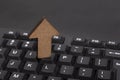 Computer keyboard and wooden up arrow. Uploading data concept
