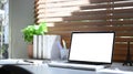 Computer laptop, books, coffee cup and houseplant beside the window with sunlight shine through the curtain Royalty Free Stock Photo