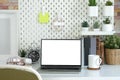 Computer laptop, books, houseplants and empty picture frame on white table Royalty Free Stock Photo