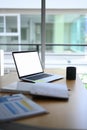 Computer laptop, coffee cup and document on wooden table. Royalty Free Stock Photo