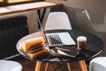 Computer laptop with coffee cup and open book on the black table