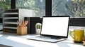 Laptop, coffee cup and potted plant on white table in home office. Blank screen for advertisement. Royalty Free Stock Photo