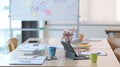 Laptop, documents and coffee cup on wooden table at bright modern conference room. Royalty Free Stock Photo