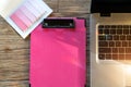 Computer laptop and pink clipboard and sticky note on working table flat lay composition top view with copy space