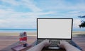 A computer or laptop placed on a wooden table, a smartphone in the hands of a person. The screen is blank white. Sea and beach Royalty Free Stock Photo