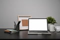 Laptop, potted plant, coffee cup and picture frame on black table. Royalty Free Stock Photo