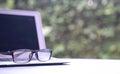 Computer laptop with reading glasses and green nature background. Work remotely or from home Royalty Free Stock Photo